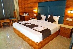 A neatly made bed with white linens, a wooden headboard, and a bedside table with a lamp. - The Park Green Resorts (Manali)
