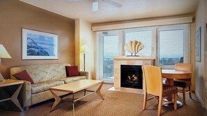 Een woonkamer met een bank, een salontafel, een open haard en een eethoek met stoelen.