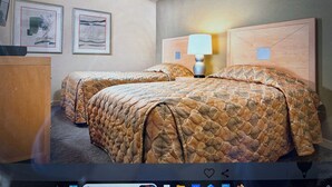 Een hotelkamer met twee bedden, een bureau, ingelijste foto's aan de muur en een lamp.