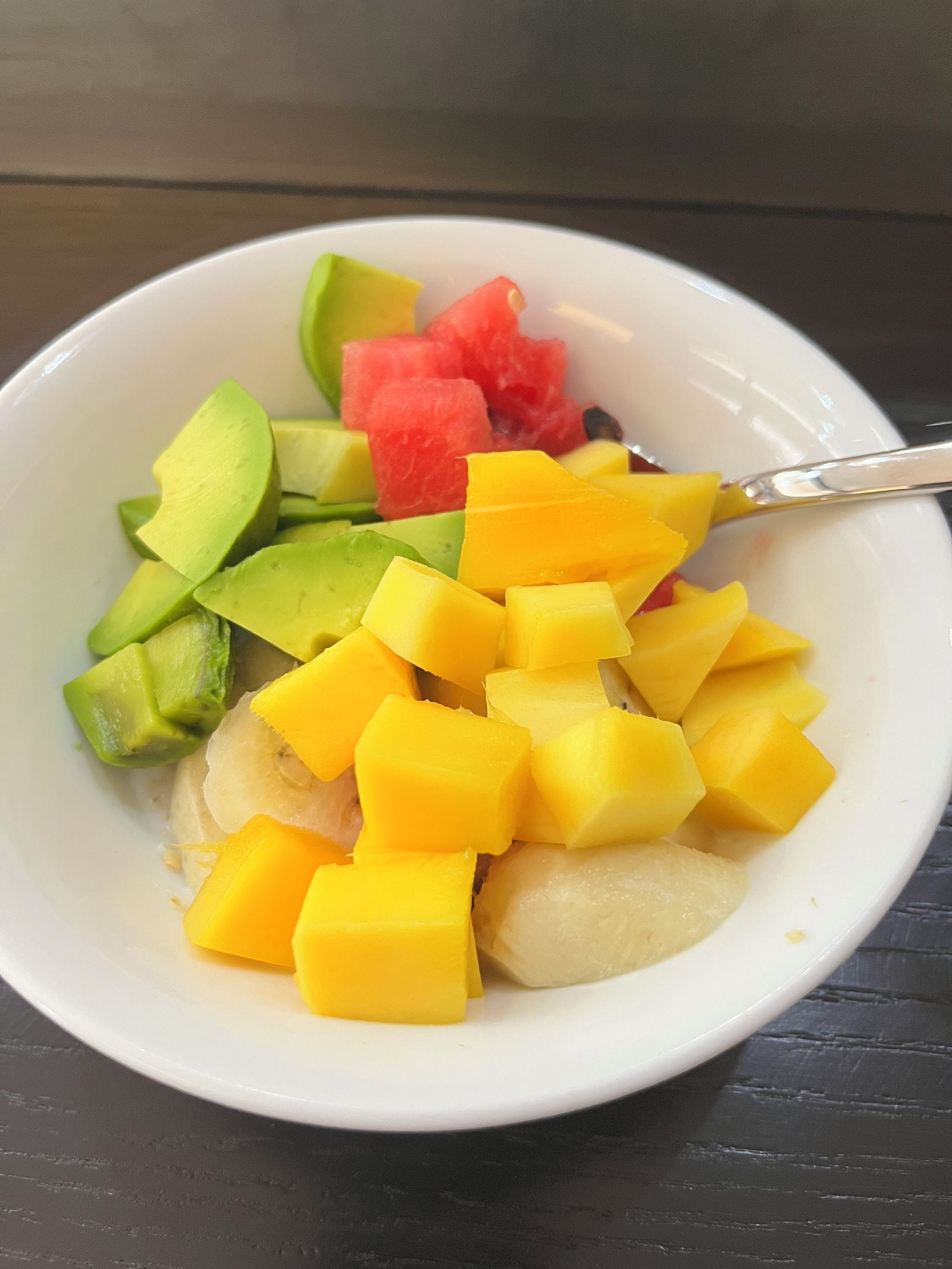 A bowl of fruit salad with a spoon.