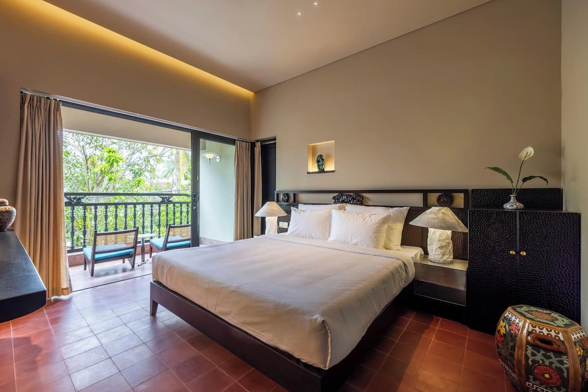Un dormitorio con una cama grande, una mesita de noche, un armario y vistas al exterior.