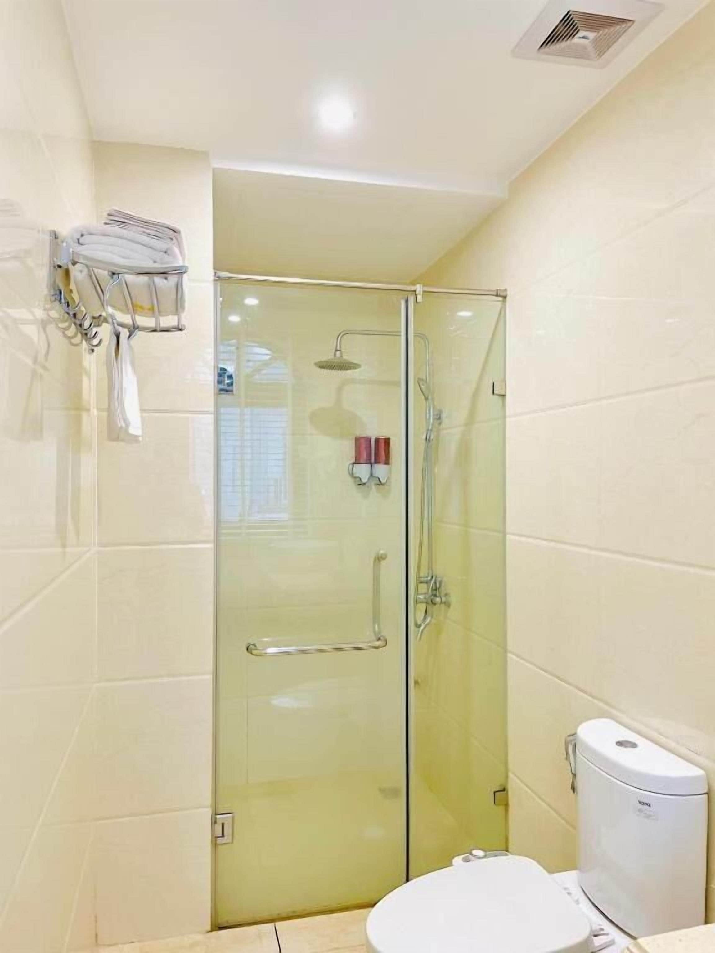 Une salle de bain avec une douche à parois de verre, des toilettes et un porte-serviettes.
