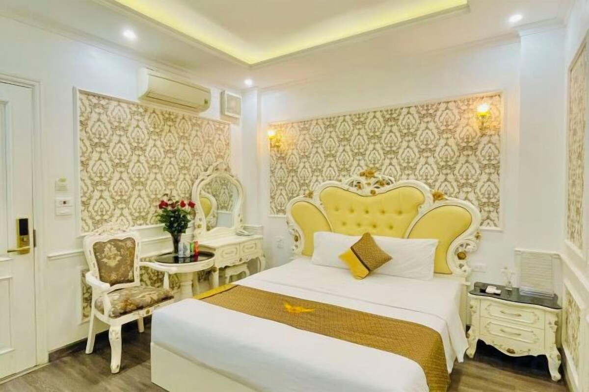 A hotel room with a large bed, a bedside table, a chair, and a decorative wall.