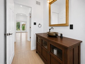 A bathroom with a wooden vanity, a round sink, a mirror, and a toilet paper holder. - Luxury group 4 Bedroom Villa 2 Kitchens, 2 Laundry Areas Resort style Pool 14 pp (Los Angeles)