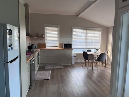 A compact kitchen with a refrigerator, microwave, stove, and dining area with chairs and a table.. Cozy country retreat