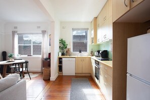 Eine kleine Küche mit Essbereich, Holzausstattung, einem Geschirrspüler und einem Kühlschrank.