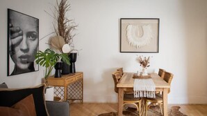 A dining area with a wooden table, chairs, a vase with dried plants, and a framed artwork on the wall. - Modern 2BR Boho Apt One Block From The Beach (Bondi Beach)