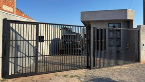 A gated property with a modern building, a parked car, and a clear sky.