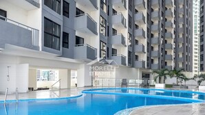 Piscina interior moderna com borda azulejada, rodeada por um edifício de vários andares com varandas e uma placa com a inscrição 