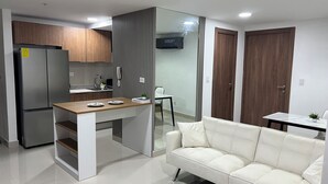 Uma cozinha moderna com frigorífico embutido, bancada de madeira e sofá branco na sala.
