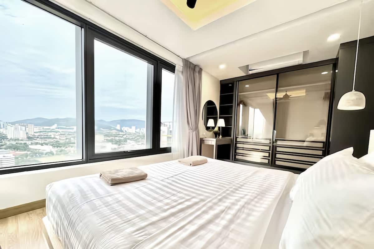Ein modernes Schlafzimmer mit großem Fenster, einem Bett, einem begehbaren Kleiderschrank und Blick auf die Stadt.