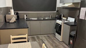 Eine moderne Küche mit grauen Schränken, einer Tafel, einer Spüle, einem Herd und einem Essbereich mit Tisch und Stühlen.