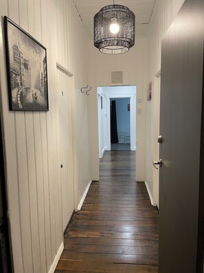 A hallway with wooden flooring, a framed picture on the left, and a hanging light fixture. - 3 bedroom Cottage Sth Grafton with ensuite, AC, WI-FI, Parkin near river & town. (South Grafton)