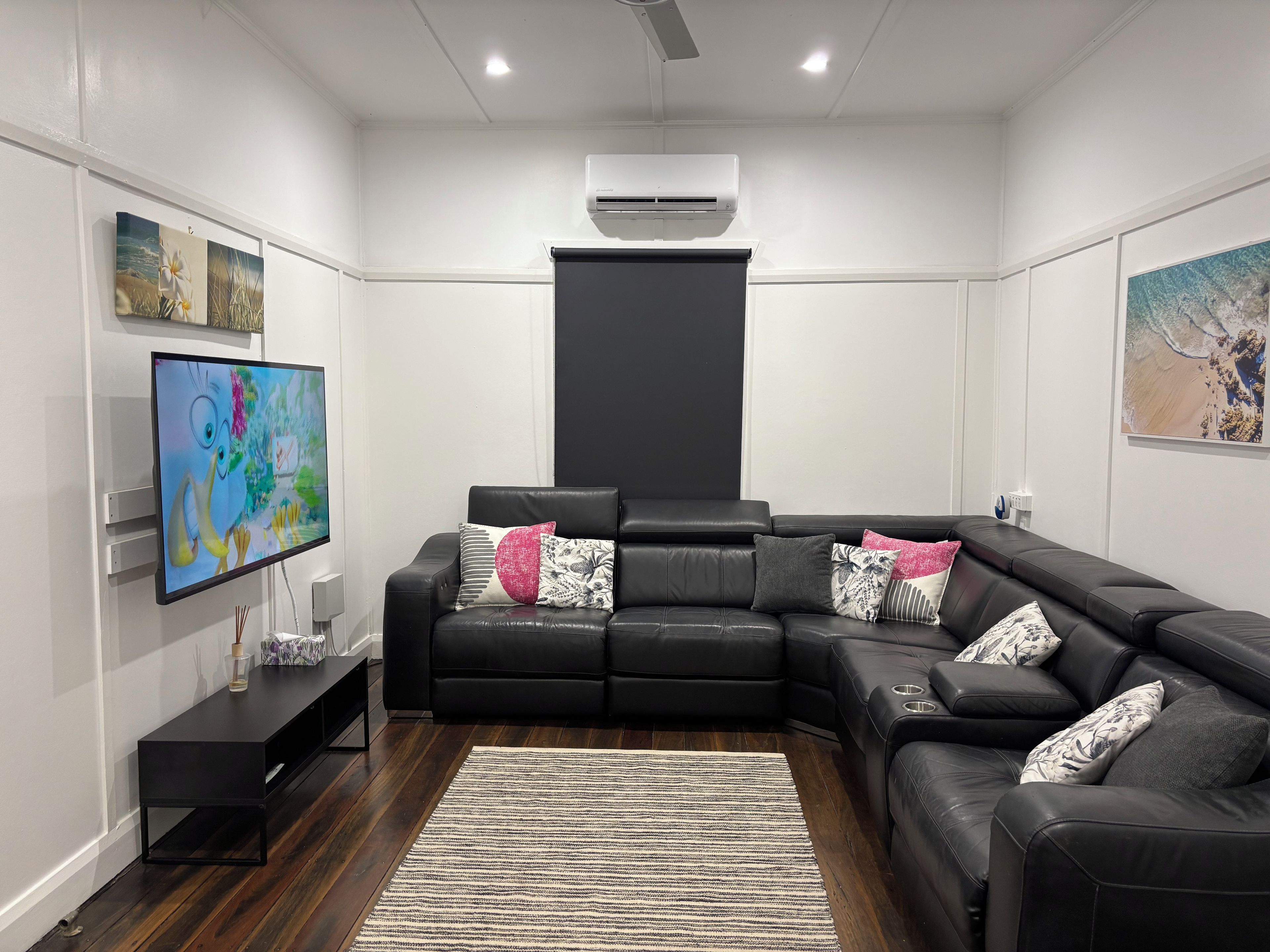 A modern living room with a sectional sofa, a flat-screen TV, and artwork on the walls.