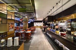Un restaurant moderne doté d’un long comptoir, de plusieurs tables et d’un espace buffet.