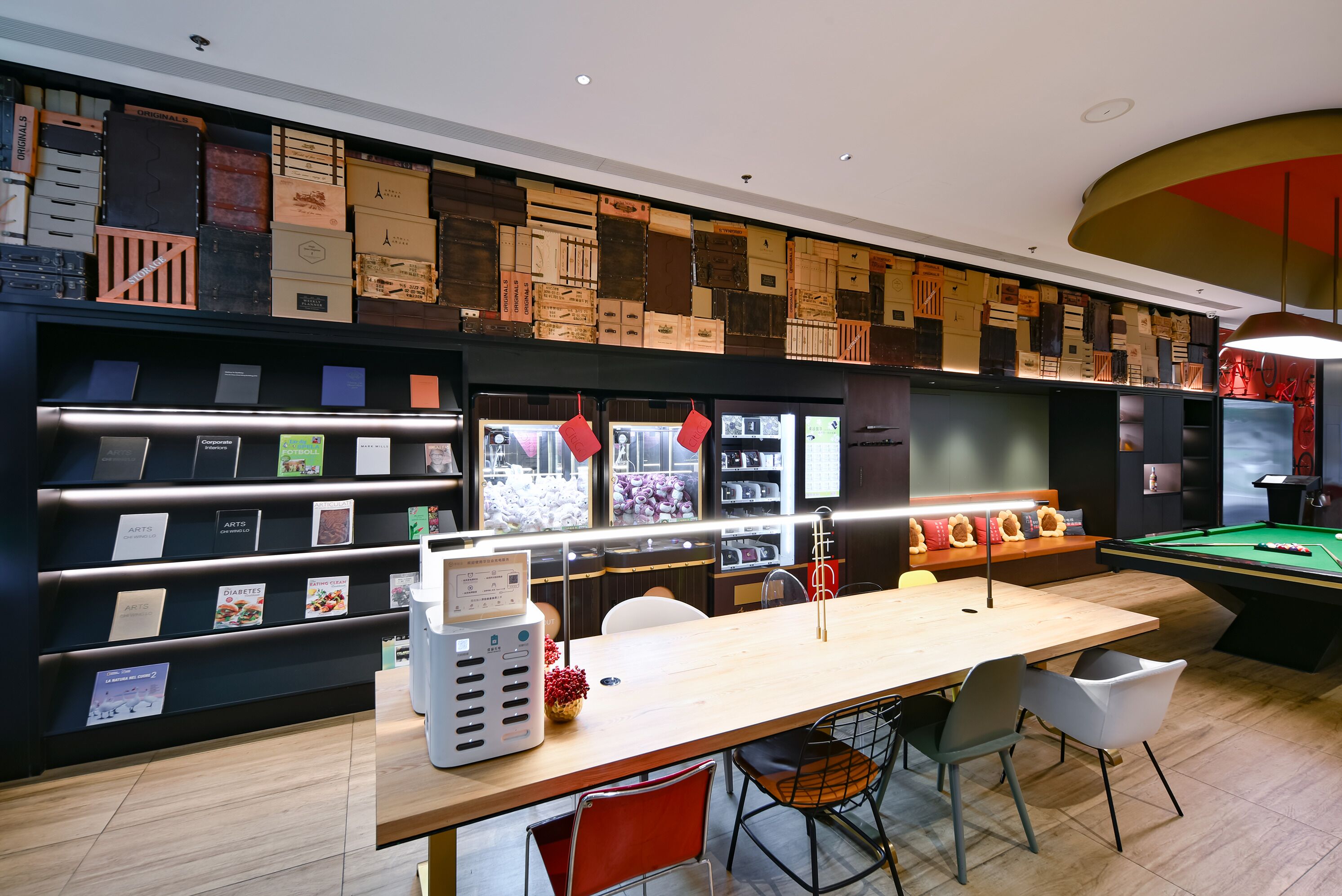 A modern lounge area with a pool table, seating, and a wall displaying various items.