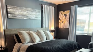 A modern bedroom with a bed, bedside tables, a bench, a ceiling fan, and artwork on the walls. - Luxury Glendale Stay with Pool & Theater Room by Cardinals Stadium (Glendale)
