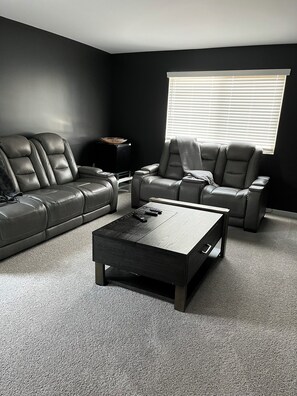 Ein modernes Wohnzimmer mit einem Ecksofa, einem Relaxsessel und einem Couchtisch.