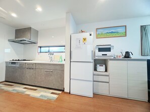 Una cocina moderna con horno empotrado, microondas y refrigerador, una ventana con vistas, y un cuadro en la pared.