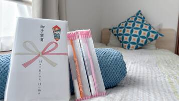 A neatly arranged bed with a blue blanket, pillows, and a white package with a ribbon.