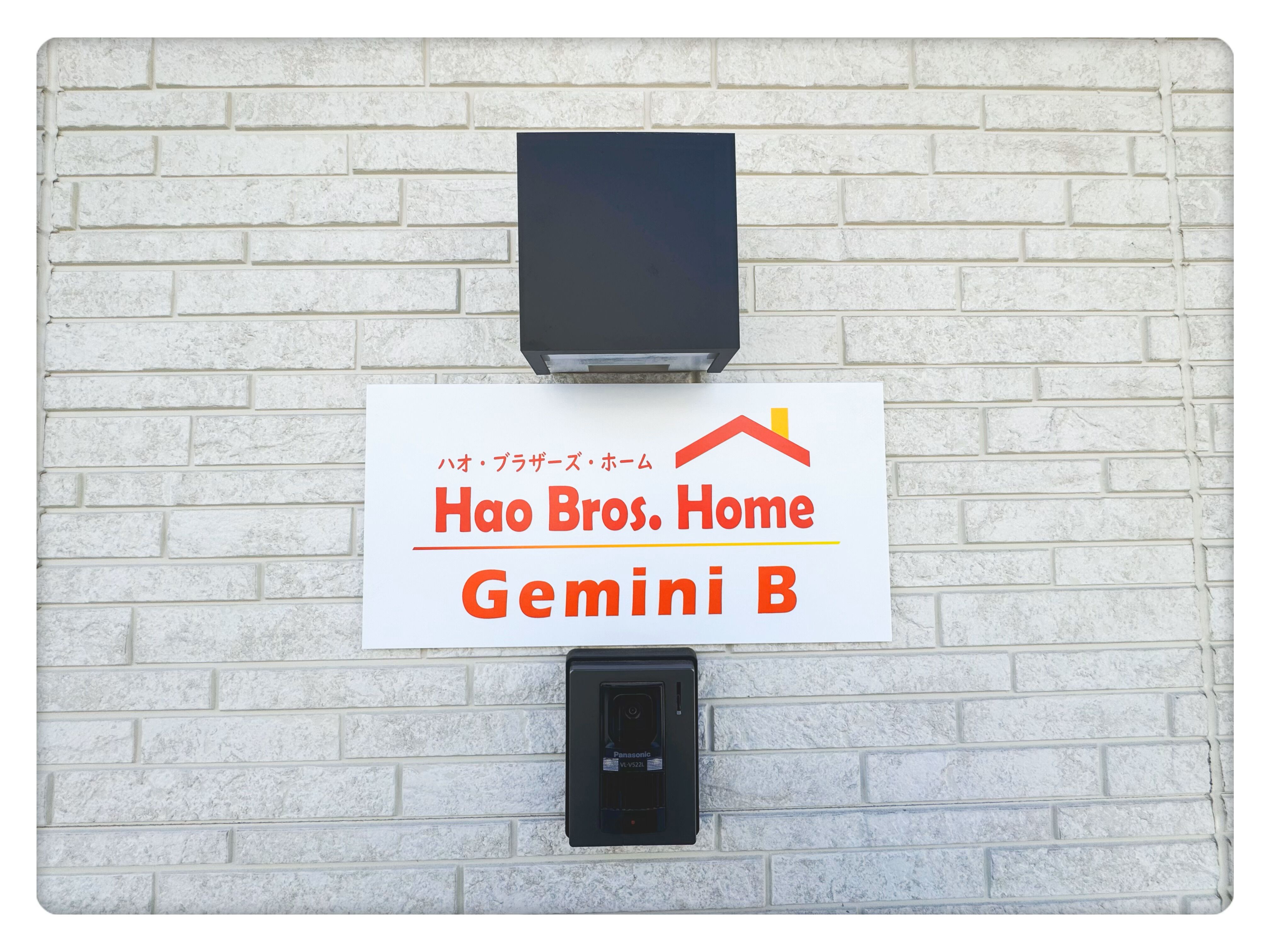 Skilt med 'Hao Bros. Home Gemini B' på en hvid murstensvæg med en sort postkasse nedenunder.
