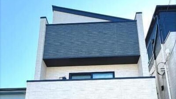 A modern building with a double garage door, a small outdoor area, and a security keypad. - Hao Bros.Home Gemini (Tokyo)