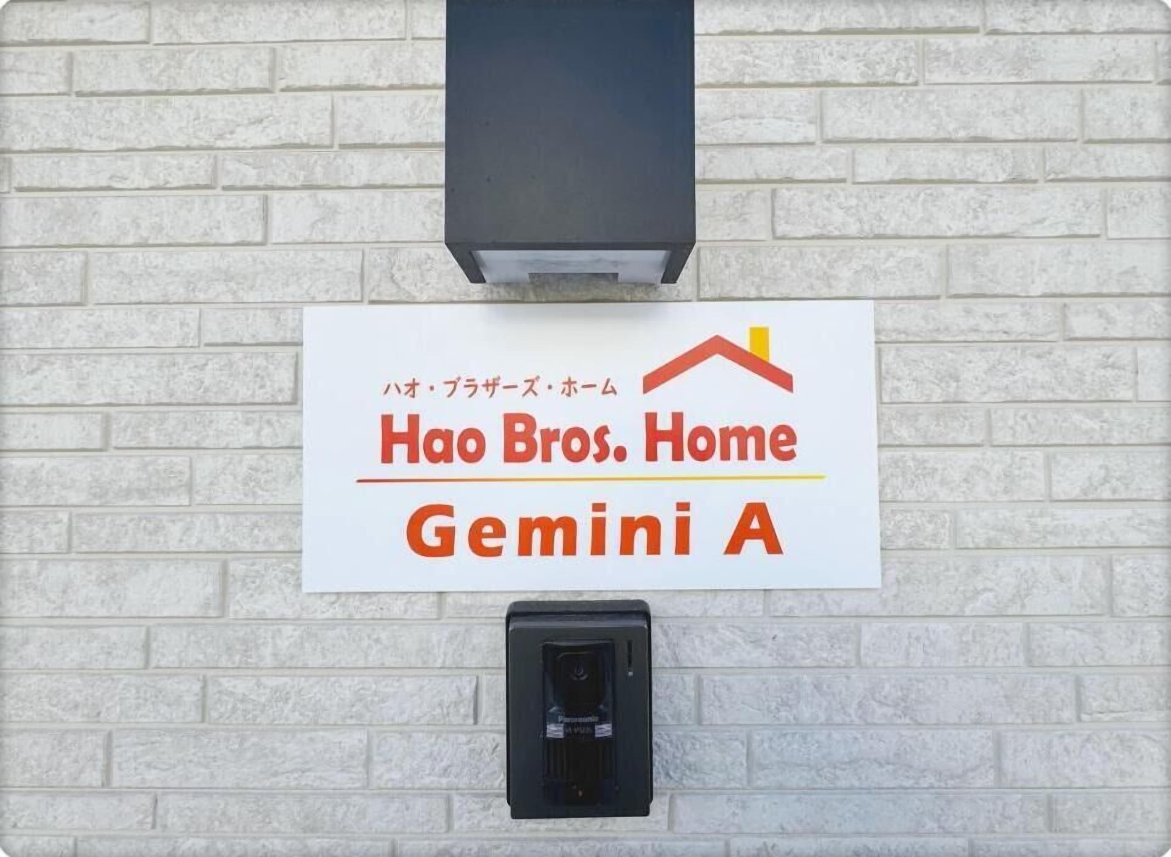 A sign for 'Hao Bros. Home Gemini A' on a white brick wall with a black electrical box below it.
