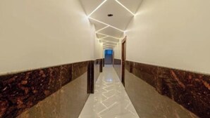 A corridor with a marble floor, white walls, and a geometric ceiling design. - Heaven Grand Ayodhya (Sohawal)