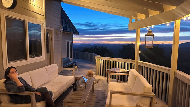 A wooden deck with a sofa, chairs, and a table.