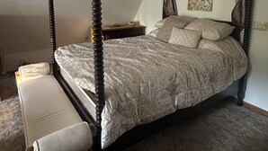 A four-poster bed with a canopy, a bedside table, and a bench.