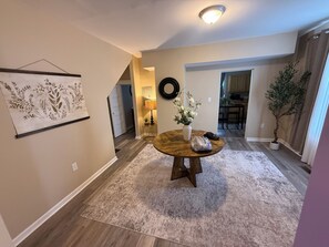 A dining area with a round table, a vase with flowers, a lamp, and a potted plant. - Charming 3BR Home - Near KDMC & Downtown (Ashland)