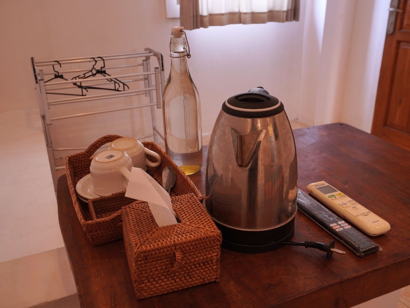 Un plan de travail de cuisine avec une bouilloire, une bouteille, un grille-pain et un panier contenant des théières.