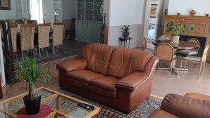 A living room with a brown leather sofa, a glass coffee table, and a patterned rug.