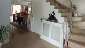 A staircase with a white railing, a white door, and a small table with a clock and decorative items.