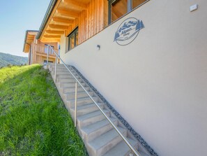 Ein Gebäude mit Holzfassade, einer Treppe, die zu einem Balkon führt, und einem Logo an der Wand.