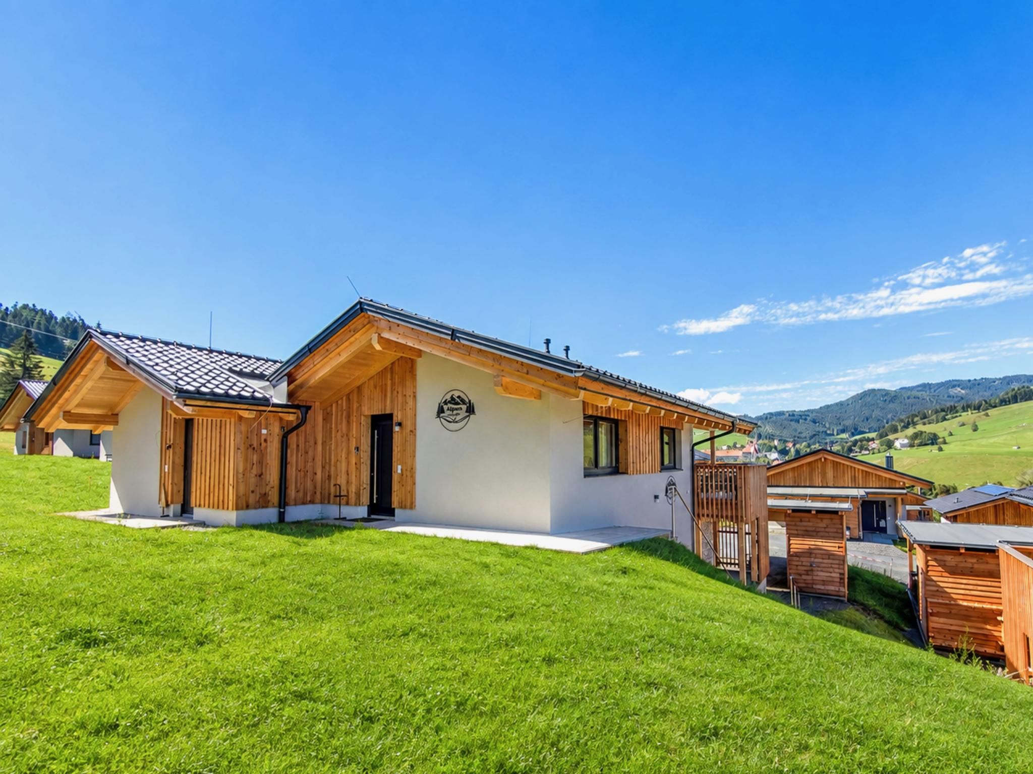 A modern wooden house with a sloped roof, a front porch, and a well-maintained lawn.