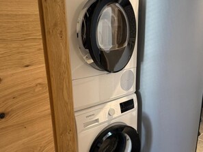 Eine Frontansicht einer übereinander angeordneten Waschmaschine und Trockner mit sichtbaren Markierungen des Herstellers.