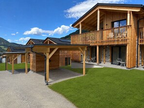 Eine Holzhütte mit Balkon, überdachter Veranda und Blick auf die Berge.