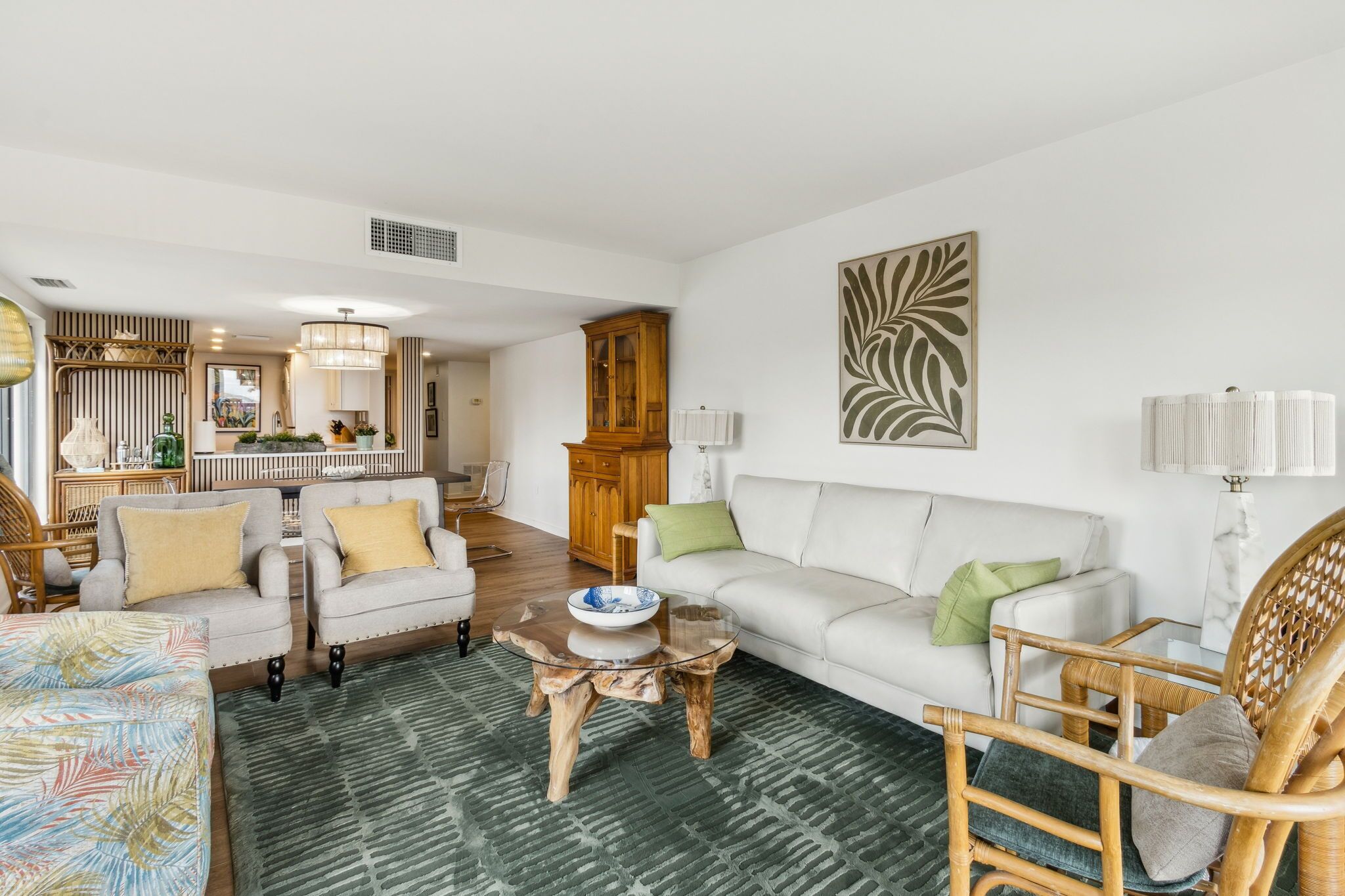 A living room with a sofa, chairs, a coffee table, and a dining area with a cabinet.