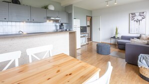 A modern kitchen with grey cabinets, a wooden dining table, and a grey sofa in the living area. - Apartment on the 8th floor with terrace (Middelkerke)