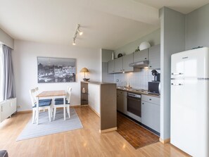 Eine moderne Küche mit Einbauofen, Kühlschrank und Essbereich mit Tisch und Stühlen.