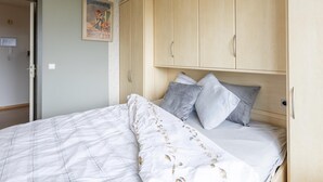 A bedroom with a bed, wooden wardrobe, and a poster on the wall. - Apartment on the 8th floor with terrace (Middelkerke)