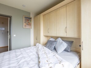 Ein Schlafzimmer mit einem Bett, einem Holzschrank und einem Poster an der Wand.