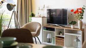Una sala moderna con televisor, un trípode, una silla y una planta en maceta.