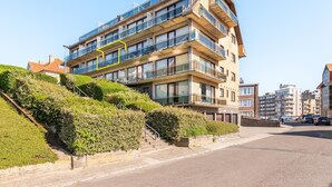 Un edificio de varios pisos con balcones, una escalera y un estacionamiento.