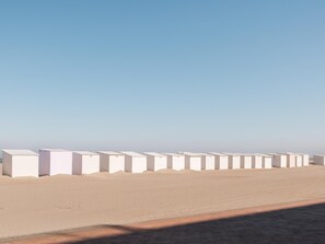 A row of white, rectangular structures with a flat roof, aligned along a paved walkway. - centrally located apartment by the beach (Koksijde)