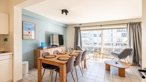 A modern apartment with a dining area, kitchenette, and a large window with a city view. - centrally located apartment by the beach (Koksijde)