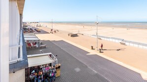 A beachside promenade with shops, a clear sky, and a sandy beach. - Tastefully furnished apartment with sea view (Koksijde)