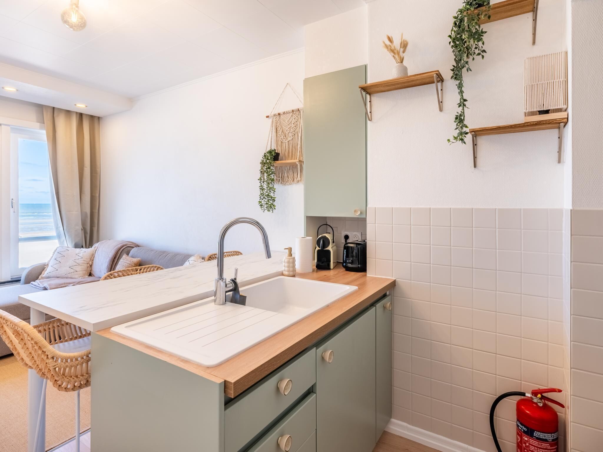 A modern kitchen with a sink, wooden cabinets, and a fire extinguisher.