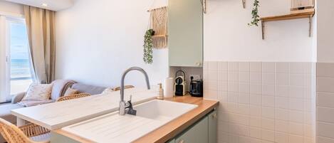 A modern kitchen with a sink, wooden cabinets, and a fire extinguisher.
